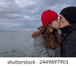 A man and woman kiss each other on the lips at Lake Ontario