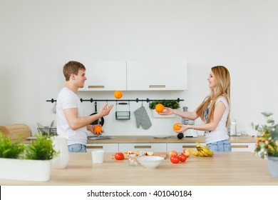 Man And Woman In The Kitchen Juggling Oranges Products. Playing And Laughing - Happy. Happy Family Life. Morning Couples.