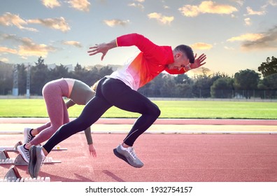 A Man And A Woman Leaving The Starting Block At The Athletics Track. 