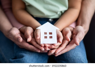 Man, Woman And Little Child Holding Cutout Paper House Figure In Hands, Conceptual Image For Family Housing, Home Mortgage, Real Estate, Insurance Or Adoption, Closeup Shot