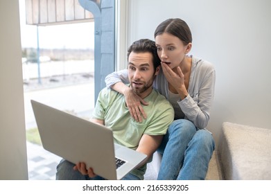 Man and woman looking inquiringly surprised at laptop