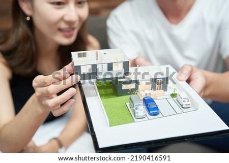 Man and woman looking at a model of a house in a room