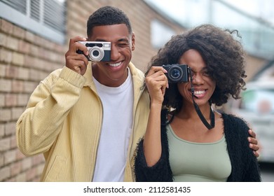 Man And Woman Looking Through Camera Lens On Street