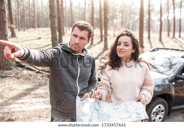 Man and woman lost in the\
forest. They are standing with a map and do not know where to go\
next.