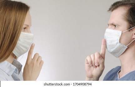 man and woman with medical mask shows hush and be quiet gesture each other