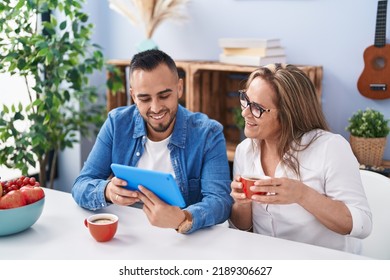 Man and woman mother and son drinking coffee using touchpad at home - Powered by Shutterstock