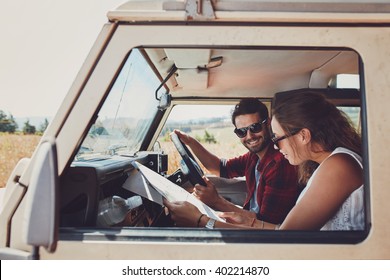 Man and woman on a road trip and reading a map together while seated inside their car. Happy young couple going on road trip. - Powered by Shutterstock