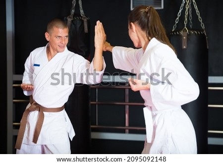 Man and woman in pairs exercising karate movements during group training