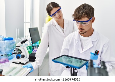 Man and woman partners wearing scientist uniform using touchpad with embryo image at laboratory