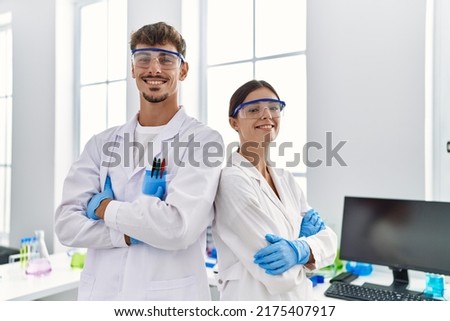 Man and woman partners wearing scientist uniform standing with arms crossed gesture at laboratory