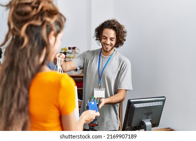 Man And Woman Paying Purchase Using Credit Card And Data Phone At Clothing Store