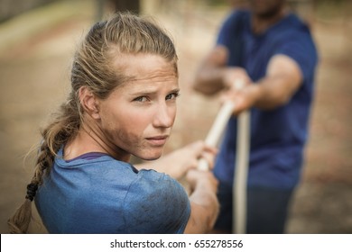 Man and woman playing tug of war during obstacle course in boot camp - Powered by Shutterstock