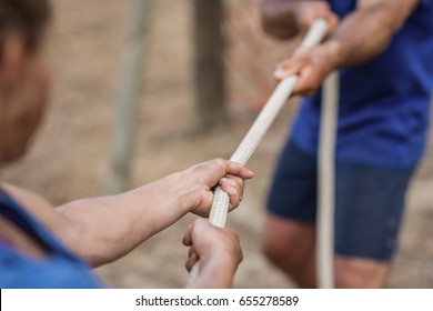 Man and woman playing tug of war during obstacle course in boot camp - Powered by Shutterstock