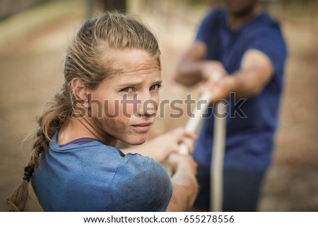 Man and woman playing tug of war during obstacle course in boot camp