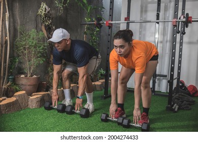 A Man And Woman Prepare To Pick Up Some Hex Dumbbells For A Set Of Romanian Deadlifts. Couple Working Out At A Home Gym.