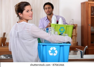 Man And Woman Preparing To Recycle Plastic Bottles