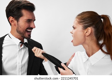 Man And Woman Pulling On Tie Anger Business Looking At Each Other Screaming With Hands Up In White Isolated Background. The Concept Of Business In A Couple Harassment Startup Copy Space