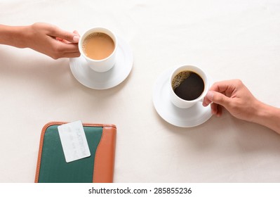 A Man And Woman Reaching For Their Coffee Cups Across A Cafe Table. Overhead Closeup With Only The Peoples Hands Being Shown.
