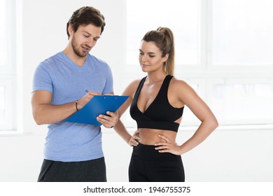 Man and woman are ready for workout in the gym. Personal fitness instructor writing individual training and diet plan for his client - Powered by Shutterstock