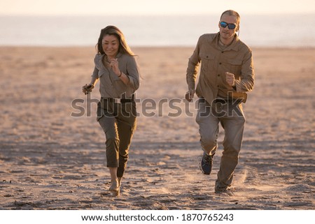 Man and woman run along the beach by the ocean in Namibia, Africa