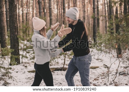 
a man and a woman run to each other against the background of a winter pine forest