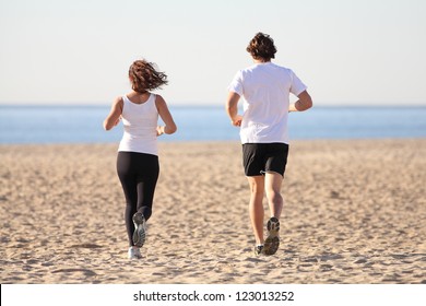 Man and woman running in the beach towards the sea - Powered by Shutterstock