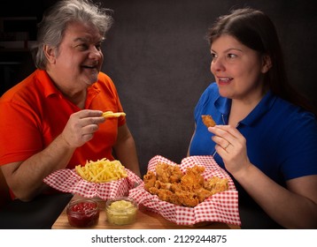 Man And Woman Sharing Fried Chicken And French Fries