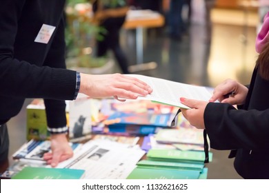 Man And Woman Sharing Information Leaflet Over Exhibition Stand