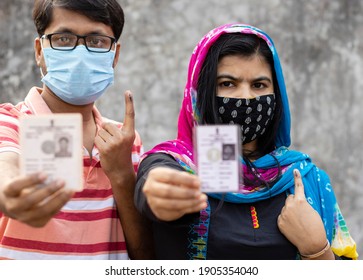 A Man And Woman Showing Ink-marked Finger And Voter Card With Safety Nose Mask On