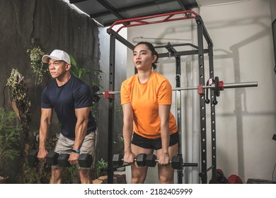 A Man And Woman Simultaneously Doing A Set Of Romanian Deadlifts. Couple Working Out At A Home Gym.