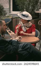 El hombre y la mujer se sientan con champán y hablan suavemente, vestidos con un elegante estilo a la antigua. Amor suave. Pareja de Antiguas enamorada. Adecuado para la cubierta. Concepto de vintage, amor, nostalgia