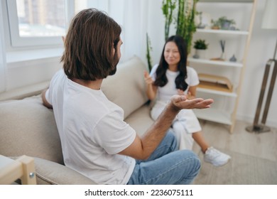 A man and a woman sit on the couch at home in white T-shirts and shouting communicate scandalously do not understand each other. A quarrel in the family of two spouses and aggression, sad emotions - Shutterstock ID 2236075111