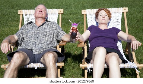 Man And Woman Sitting In Hammocks In Their Backyard Enjoying A Tropical Drink