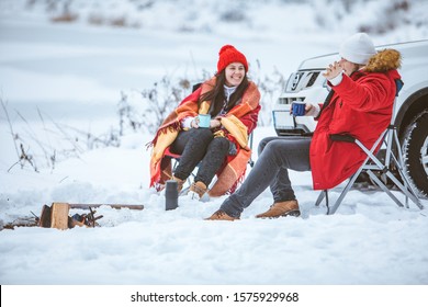 man with woman sitting on chairs near camp fire in winter time. car travel. - Powered by Shutterstock