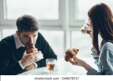 A man and a woman are sitting at the table and eating croissants