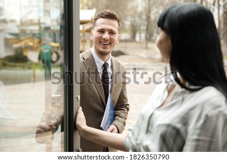 A man and a woman are smiling at each other. They are in the office building