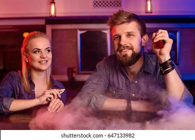 A man and woman smoking electronic cigarette in a vape bar. - Powered by Shutterstock