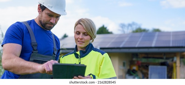 Man and woman solar installers engineers with tablet while installing solar panel system on house. - Powered by Shutterstock