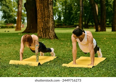 A man and a woman in sportswear demonstrating strength and determination as they perform push ups in a park - Powered by Shutterstock