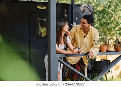 A man and a woman stand on a balcony, overlooking a scenic view, embracing each other in a serene moment of togetherness. - Powered by Shutterstock