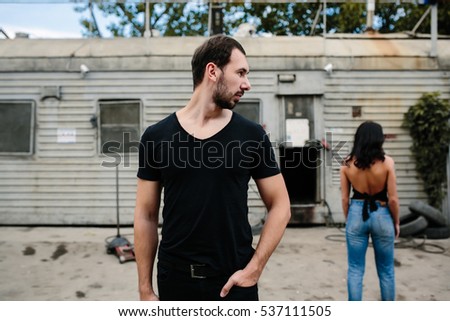 man and woman standing backs to each other on a background gray wall