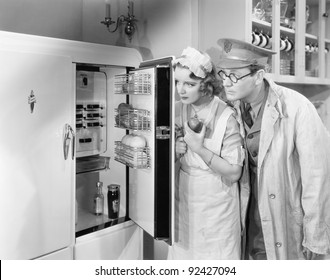 Man And Woman Standing In Front Of A Refrigerator