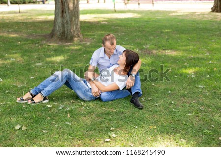 man and woman standing on the lawn. in a white t-shirt and jeans. a walk in the Park. lover. young couple. summer. family. girl and guy . couple smiles
