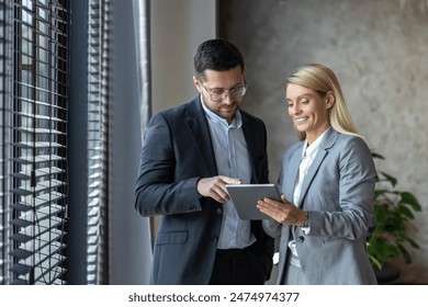 Man and woman standing with tablet discussing professional ideas - Powered by Shutterstock