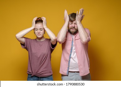 Man and a woman suffer from headaches, they hold their heads with their hands, closing their eyes. Health concept. 