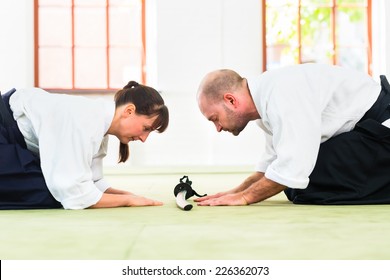 Man and woman take a bow to greet at Aikido martial arts school 