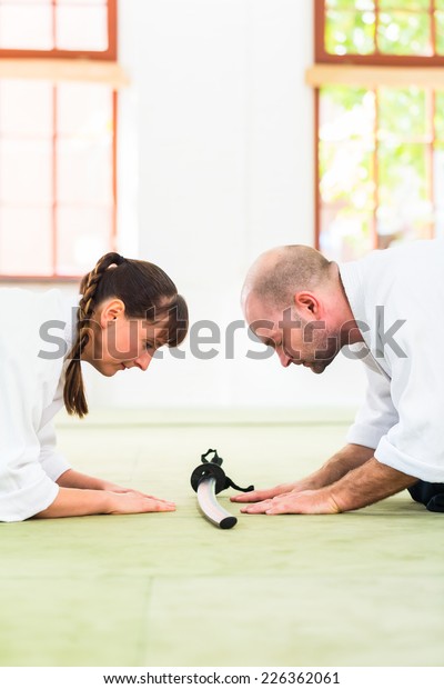 Man and woman take a bow to greet at Aikido martial arts\
school 