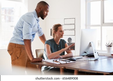 Man And Woman Talk In An Office Looking At Computer Screen