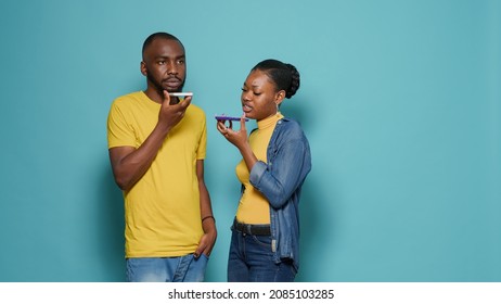 Man And Woman Talking On Phone Call With Smartphone On Speaker In Studio. Couple Using Mobile Phone To Have Online Conversation Together In Front Of Camera. Modern People With Technology