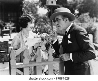 Man And Woman Talking Over A Picket Fence